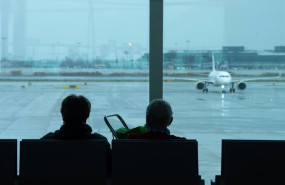 ep archivo   dos personas esperan sentadas frente a un avion aparcado en la pista del aeropuerto de