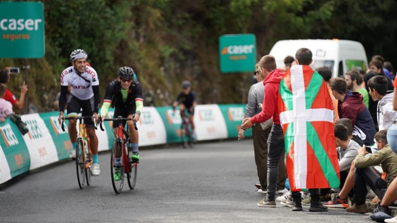 Ambiente cerca de Bilbao horas antes de la llegada de la XII etapa de la Vuelta Ciclista a Bilbao. En la imagen, dos aficionados en bici y otro envuelto en la Ikurriña. | H.Bilbao - Europa Press ep ambiente cerca de bilbao horas antes de la llegada de la xii etapa de la vuelta ciclista a bilbao