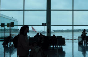 ep varias personas esperan sentadas frente a un avion aparcado en la pista del aeropuerto de el prat