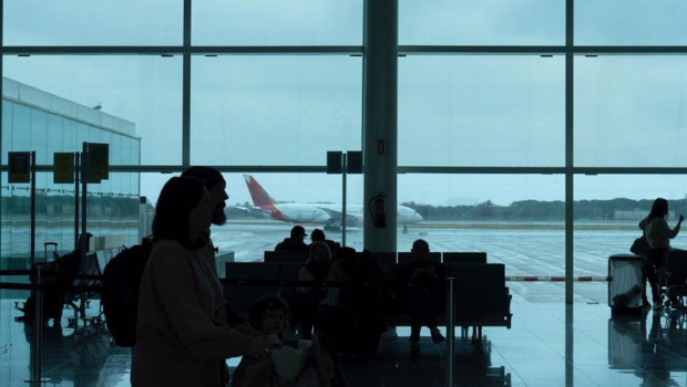 ep varias personas esperan sentadas frente a un avion aparcado en la pista del aeropuerto de el prat
