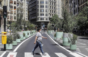 ep un hombre cruza por un paso de cebra al lado de los maceteros colocados en la plaza del