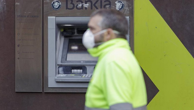 ep un trabajador con chaleco y mascarila pasa delante de un cajero de bankia