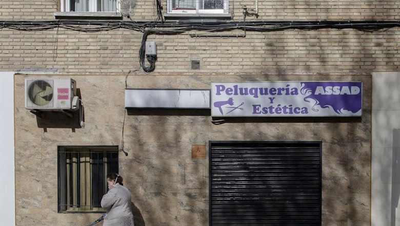 Una mujer pasea a un perro cerca de una peluquería cerrada durante el primer día laborable desde que se decretó el estado de alarma en todo el territorio nacional a consecuencia del coronavirus, en Alcorcón (Madrid), a 16 de marzo de 2020. | Eduardo Parra - Europa Press ep una mujer pasea a un perro cerca de una peluqueria cerrada durante el primer dia laborable desde
