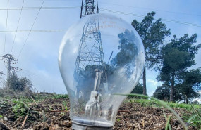 ep archivo   una bombilla clavada el cesped delante de una torre de energia electrica