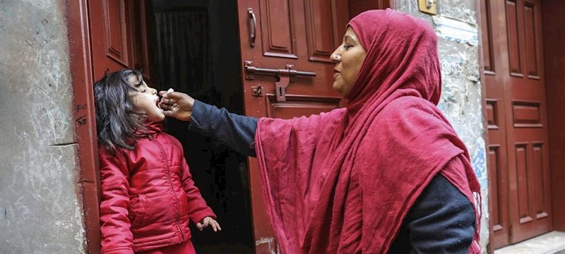 Una trabajadora sanitaria vacuna a una niña de 4 años contra la polio en la puerta de su casa en el área de Lahore, en Pakistán. | UNICEF/ASAD ZAIDI ep una trabajadora sanitaria vacuna a una nina de 4 anos contra la polio en la puerta de su casa en