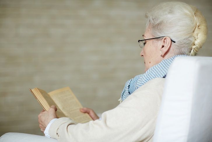 concentrated retired woman reading old book