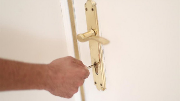 ep un hombre introduce una llave en la cerradura de la puerta de una vivienda