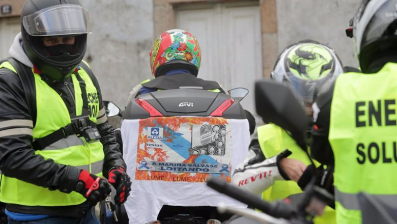ep un hombre lleva enganchada a su moto una pancarta donde se lee a marina se salva luchando antes
