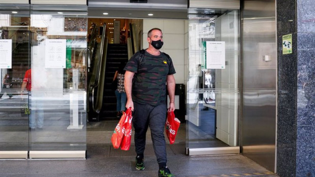ep un hombre sale con varias bolsas de un centro comercial