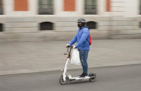ep una persona totalmente protegida se traslada con un patinete electrico por el centro de la