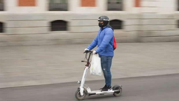 ep una persona totalmente protegida se traslada con un patinete electrico por el centro de la