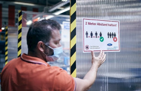 ep un empleado de ford colocando un cartel que pide distanciamiento entre los trabajadores para