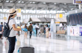 ep turistas en aeropuerto con maleta y mascarilla