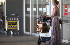 ep archivo   una mujer protegida con mascarilla llega con su equipaje a la terminal t1 del