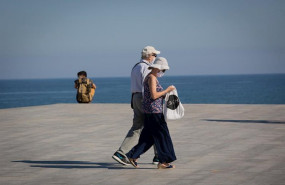 ep dos personas protegidas con mascarillas pasean por el paseo maritimo de la playa de la