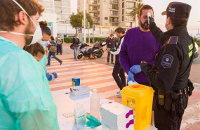 ep un agente de la policia portuaria mide la temperatura a un visitante en formentera