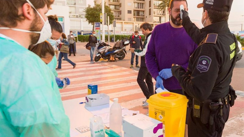 ep un agente de la policia portuaria mide la temperatura a un visitante en formentera