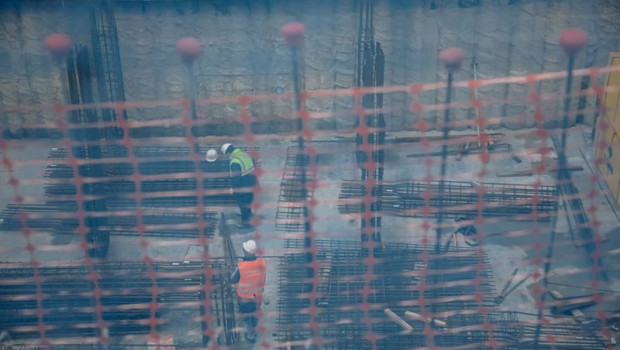 ep vista de dos obreros trabajando en el forjado de una obra a traves de una red de seguridad en