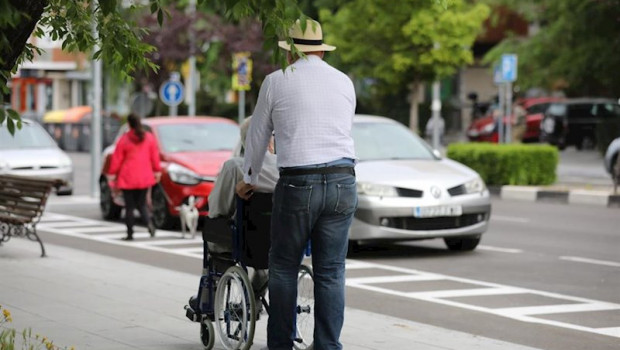 ep un hombre pasea a una persona de edad avanzada en silla de ruedas durante su franja horaria
