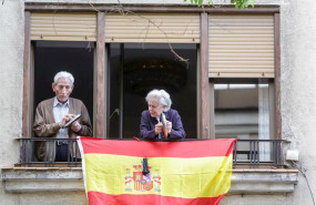 ep un hombre y una mujer asomados a su balcon hacen sonar tapas de cacerolas durante la cacerolada