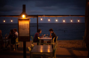 ep dos jovenes en la terraza de un restaurante frente a la playa de la barceloneta