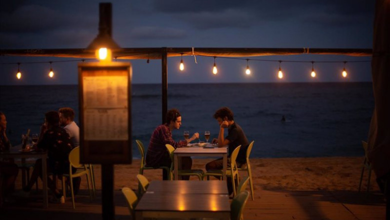 ep dos jovenes en la terraza de un restaurante frente a la playa de la barceloneta