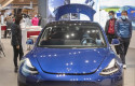 ep imagen de un modelo de tesla con personas con mascarillas a su alrededor