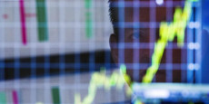 a-trader-looks-up-at-a-chart-on-his-computer-screen-while-working-on-the-floor-of-the-new-york-stock-exchange-in-new-york