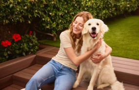 ep una mujer sentada junto a un perro en una zona ajardinada