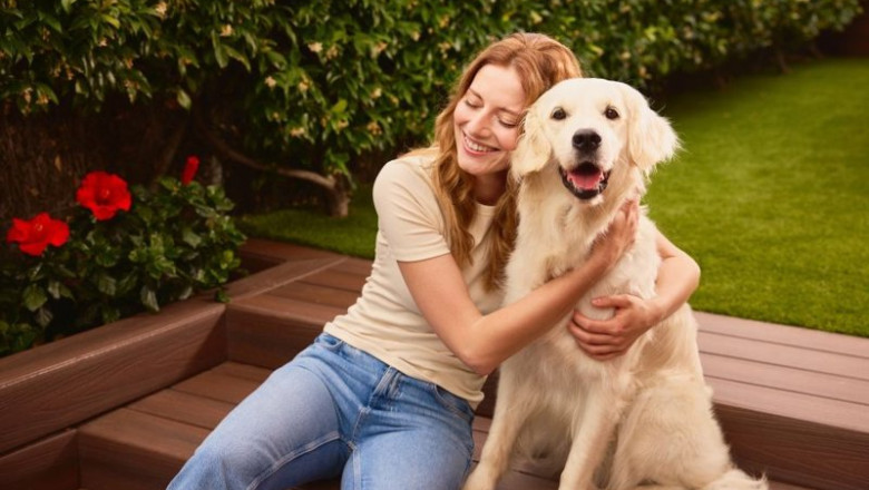ep una mujer sentada junto a un perro en una zona ajardinada