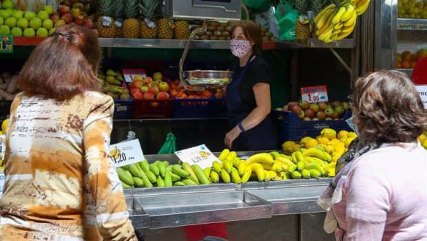 ep una trabajadora de una fruteria del mercado central de valencia atiende a dos clientas